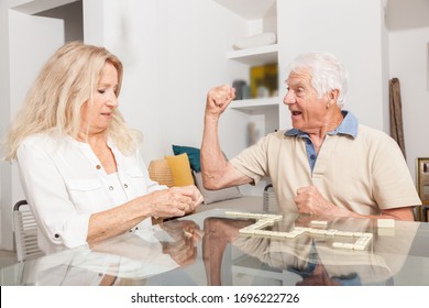 Happy Senior Couple Playing Game Dominoes.
