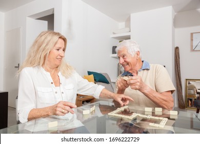 Happy Senior Couple Playing Game Dominoes.
