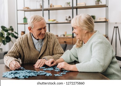 happy senior couple playing with puzzles at home