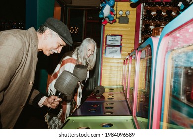 Happy Senior Couple Playing Whack A Mole At A Game Arcade