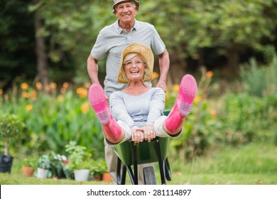 Happy senior couple playing with a wheelbarrow in a sunny day - Powered by Shutterstock