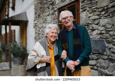 Happy Senior Couple Posing Near Old Countryside House.