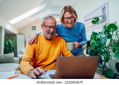 Happy senior couple reading good news on a laptop at home and using internet together. Smiling elderly spouses reading a mail, checking paying bills online, discussing budget planning. - Powered by Shutterstock