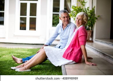 Happy Senior Couple Relaxing On Steps Outside House