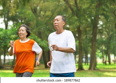 Happy Senior Couple Running Together In The Park