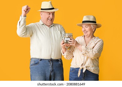 Happy Senior Couple With Savings In Jar On Color Background