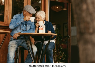 Happy senior couple sitting at coffee shop and talking. Elderly man and woman relaxing at cafe and having coffee. - Powered by Shutterstock