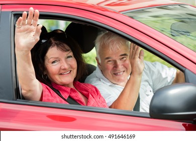 Happy Senior Couple Sitting Inside Car Waving Goodbye