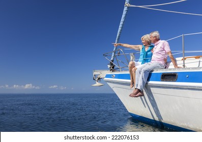 A Happy Senior Couple Sitting On The Side Of A Sail Boat On A Calm Blue Sea Looking And Pointing To A Clear Horizon