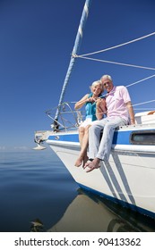 A happy senior couple sitting on the deck of a sail boat on a calm blue sea