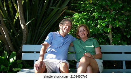 Happy Senior Couple Sitting Outside At Park Bench