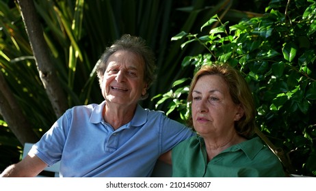 Happy Senior Couple Sitting Outside At Park Bench