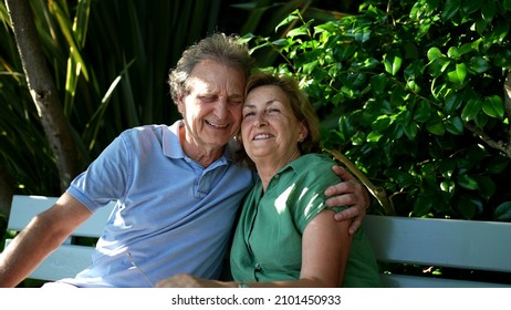 Happy Senior Couple Sitting Outside At Park Bench