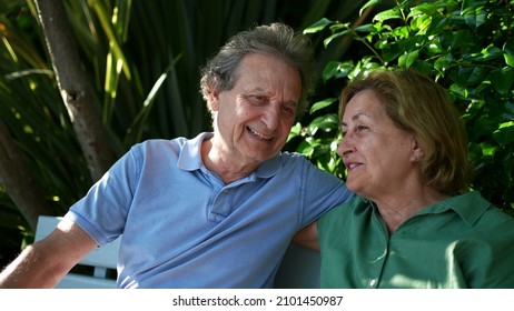 Happy Senior Couple Sitting Outside At Park Bench