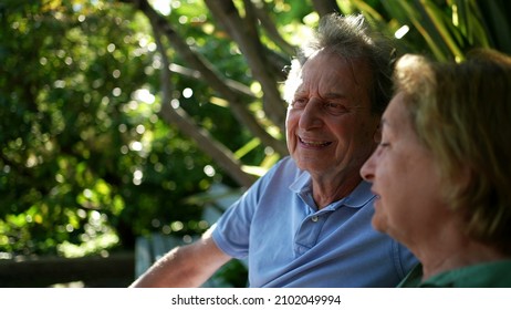 Happy Senior Couple Sitting Outside At Park Bench