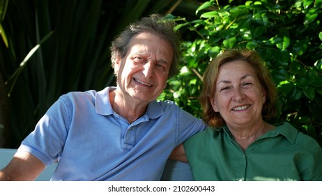 Happy Senior Couple Sitting Outside At Park Bench