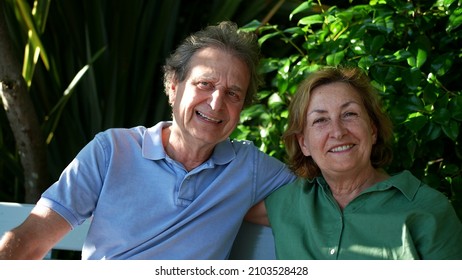 Happy Senior Couple Sitting Outside At Park Bench