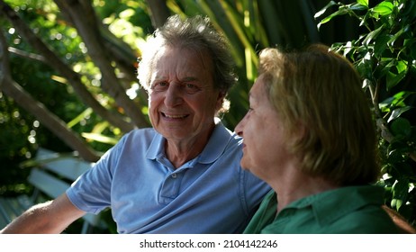 Happy Senior Couple Sitting Outside At Park Bench