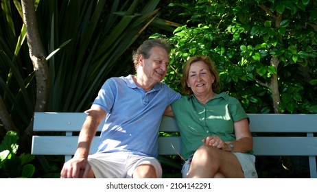 Happy Senior Couple Sitting Outside At Park Bench