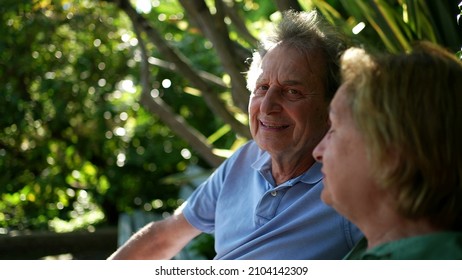 Happy Senior Couple Sitting Outside At Park Bench