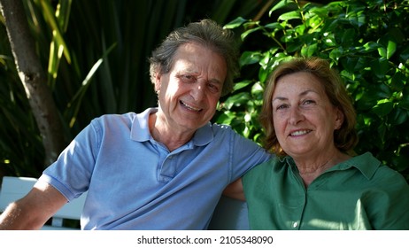 Happy Senior Couple Sitting Outside At Park Bench