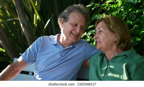 Happy Senior Couple Sitting Outside At Park Bench