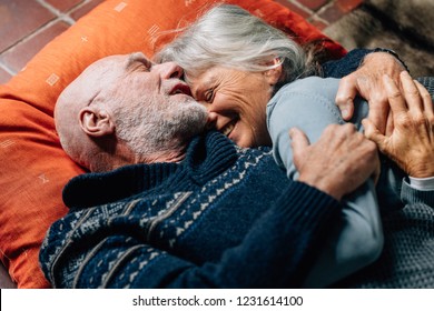 Happy Senior Couple Sleeping On Floor Hugging Each Other On A Cold Night. Smiling Senior Woman Sleeping In The Arms Of Her Husband Happily.