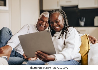 Happy senior couple smiling cheerfully while having a video call on a digital tablet. Senior couple communicating with their loved ones online. Mature couple enjoying their retirement at home. - Powered by Shutterstock