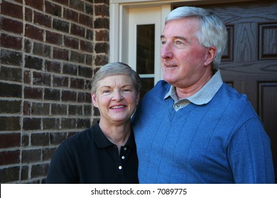 Happy Senior Couple Smiling Outside In Front Of Their House