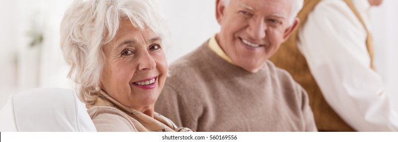 Happy senior couple smiling and sitting on a sofa - Powered by Shutterstock