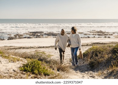 낭만적인 소풍이 끝난 후 해변을 걸어가다가 웃는 행복한 노부부가 있다. 명랑한 노부부는 은퇴 후 바닷가 휴가를 즐기고 있다. 스톡 사진