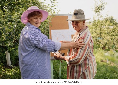 HAPPY SENIOR COUPLE spend time together in their garden or nature. Man is painting, love, romance, communication. Growing old beautifully together. Vibrant green garden - Powered by Shutterstock