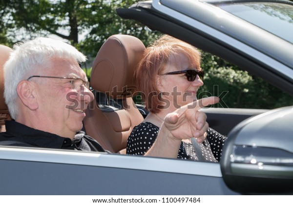 Happy senior\
couple in sports car on a sunny\
day