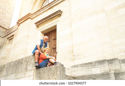 Happy Senior Couple Taking Selfie Together In San Marino Old Town Castle - Active Elderly And Travel Lifestyle Concept With Retired Mature People At Italy Roadtrip - Soft Sunshine Halo Warm Filter