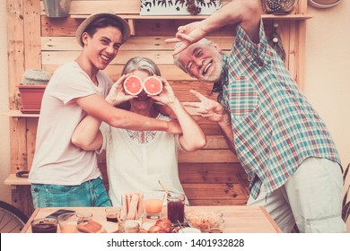 Happy senior couple with teenager nephew have fun at breakfast. Craziness and laughs. Wood on background and on table.Three people enjoying life. Food and drink - Shutterstock ID 1401932828