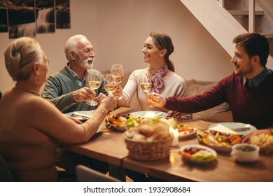 Happy Senior Couple And Their Adult Children Toasting With Wine During Dinner At Dining Table. 