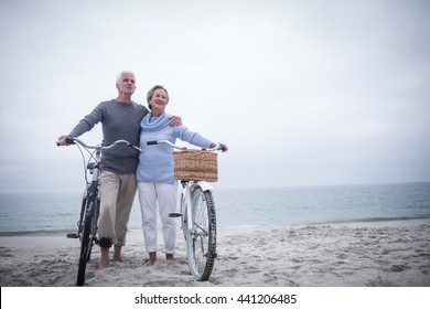 Happy senior couple with their bike on the beach