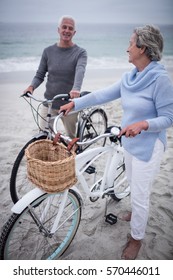 Happy Senior Couple With Their Bike On The Beach