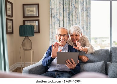 Happy senior couple using digital tablet for video conference and waving hand. Old man and smiling wife using digital tablet for video call with nephews or friends.