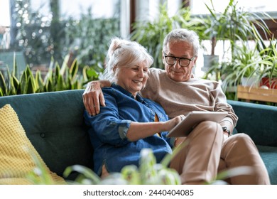 Happy senior couple using digital tablet while sitting on sofa in living room
 - Powered by Shutterstock