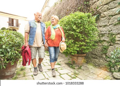 Happy Senior Couple Walking Holding Hand In San Marino Old Town Castle - Active Elderly And Travel Lifestyle Concept With Retired Mature People At Italy Roadtrip - Sunshine Halo With Sunflare Filter