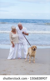 Happy Senior Couple Walking On The Beach With Dog