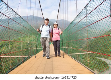 happy senior couple walking on the bridge in the nature park