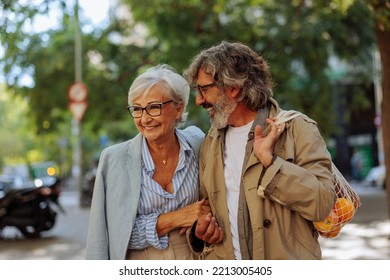 A Happy Senior Couple Are Walking Outside In The City And Are Laughing And Having A Good Time Together On A Sunny Day.