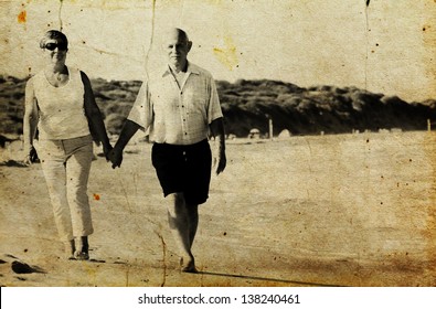 Happy Senior Couple Walking Together On A Beach. Photo In Old Image Style.