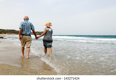 Happy Senior Couple Walking Together On A Beach