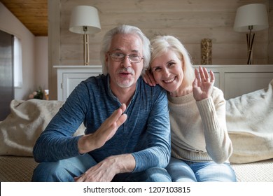 Happy senior couple wave having video call on laptop talking with relatives, smiling aged husband and wife sit on couch at home communicating via online using computer. Elderly and technology concept - Powered by Shutterstock