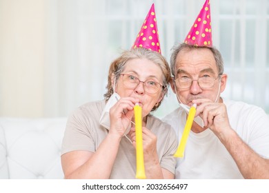 Happy senior couple wearing party's caps and blowing in pipe celebrate  birthday together during the coronavirus epidemic - Powered by Shutterstock