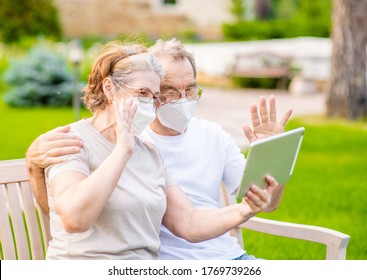 Happy Senior Couple Wearing Protective Masks Having Video Chat On Tablet Computer During The Coronavirus Epidemic