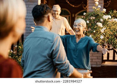 Happy senior couple welcoming their son and his wife who came to visit them. Focus is on senor woman. - Powered by Shutterstock